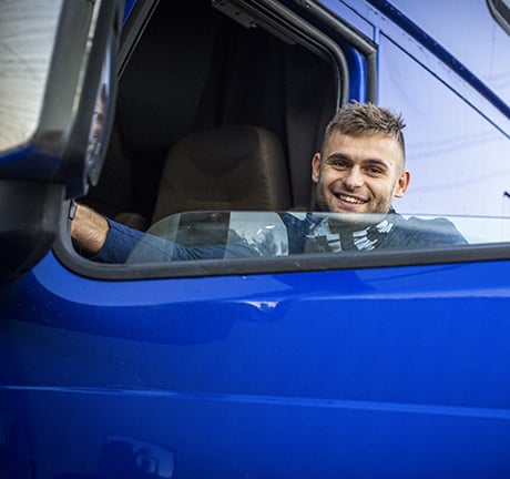 man smiling, looking at the camera through the window of the truck