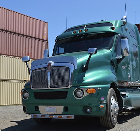 Image of a teal green truck in a container yard