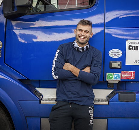 Male driver leaning up against a blue truck