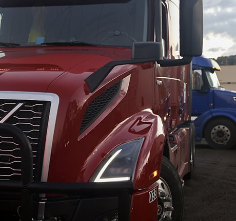 close up image of a red truck with a blue truck in the background