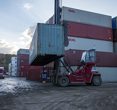 image of a container fork-lift, lifting a a container in a container yard