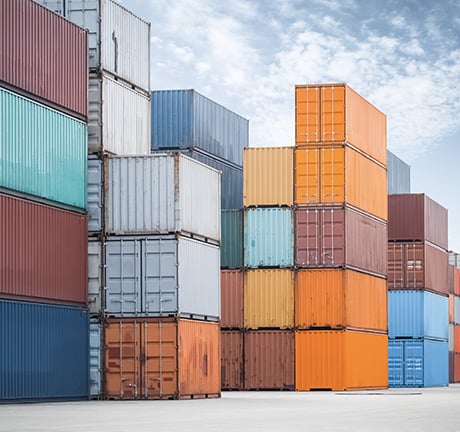 Shipping containers stacked at various heights, with a cloudy sky in the background