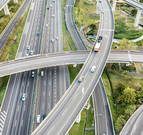 A sky-view of a highway system. roads and overpasses overlap each other with cars driving in both directions. 