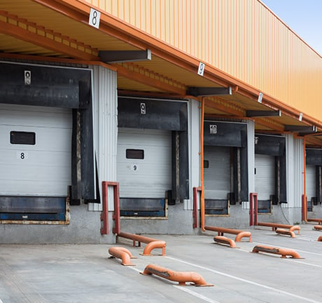 5 white garage doors under an orange roof. This is an image of a docking station. 